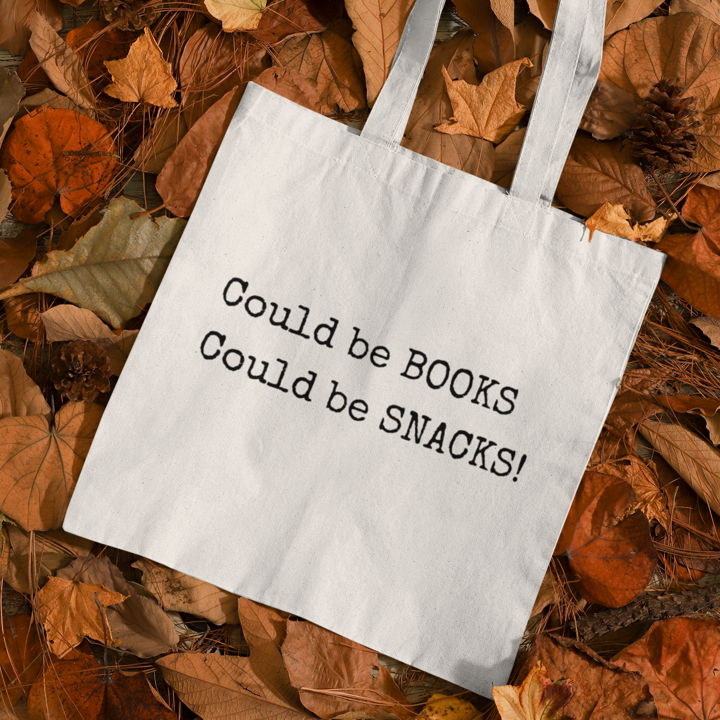 White Could Be Snacks Book Quotes Minimalist Tote Bag displayed on autumn leaves, aesthetic fall-themed eco tote for bookworms