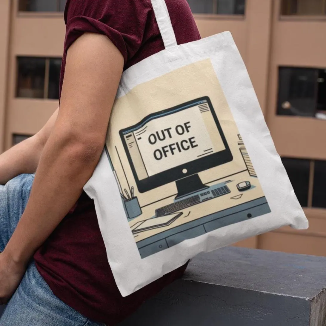 White Out of Office Design Graphic Tote Bag being used by a person, showing computer desk with Out of Office text