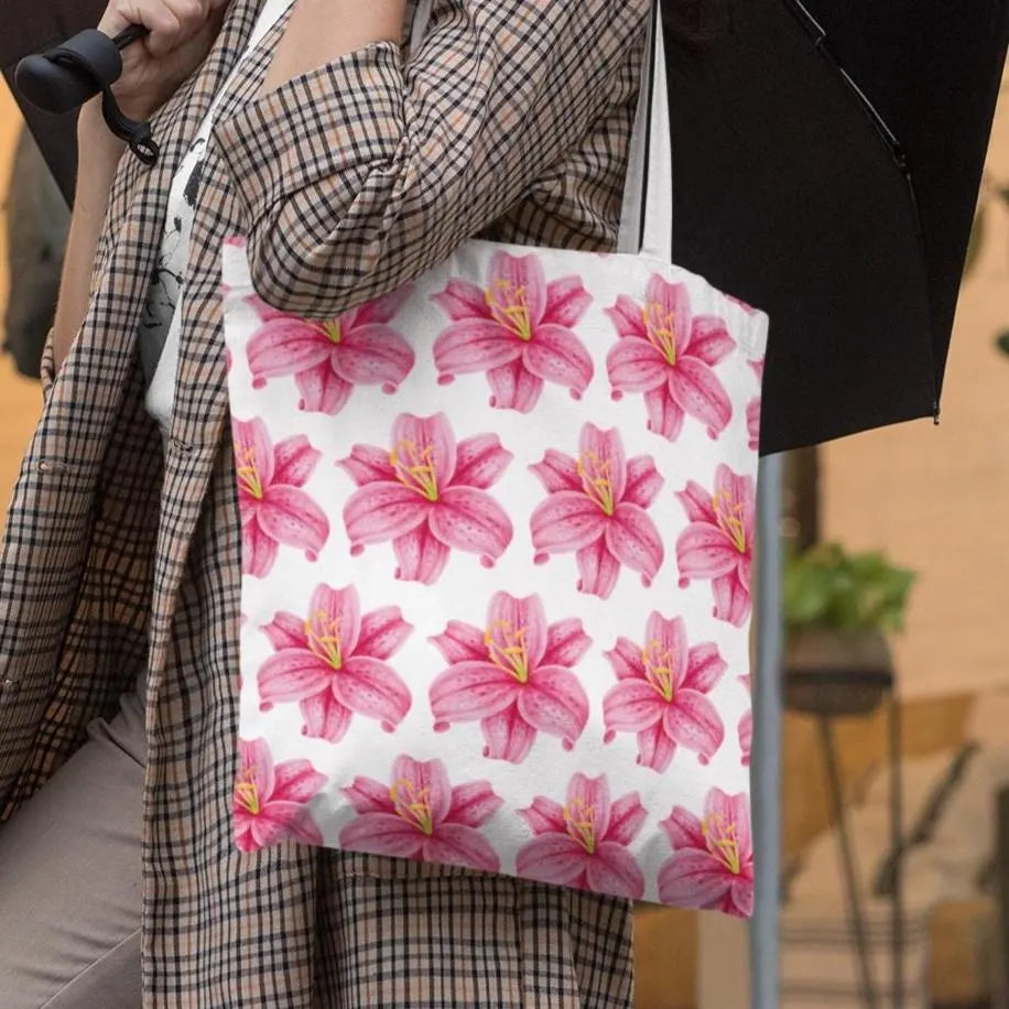 Woman in plaid coat holding pink lily flower patterned tote bag outdoors