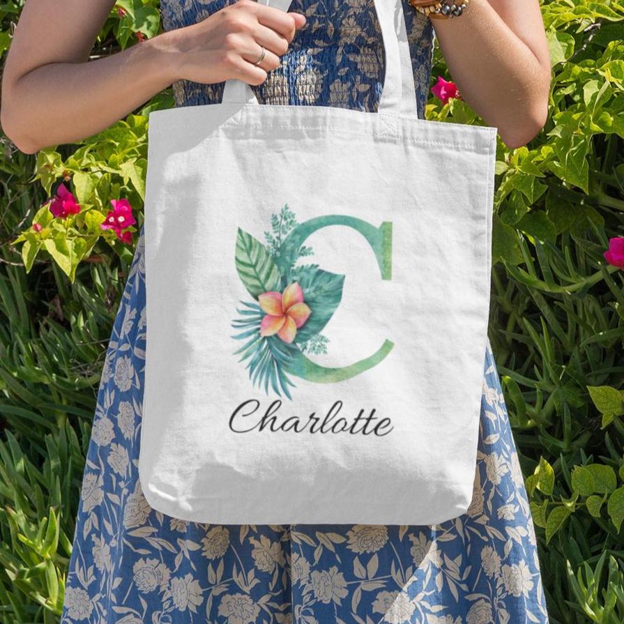 Charlotte carrying Plumeria Tropical Floral Custom Tote Bag with Emerald Green Initial C, tropical floral personalized tote outdoors