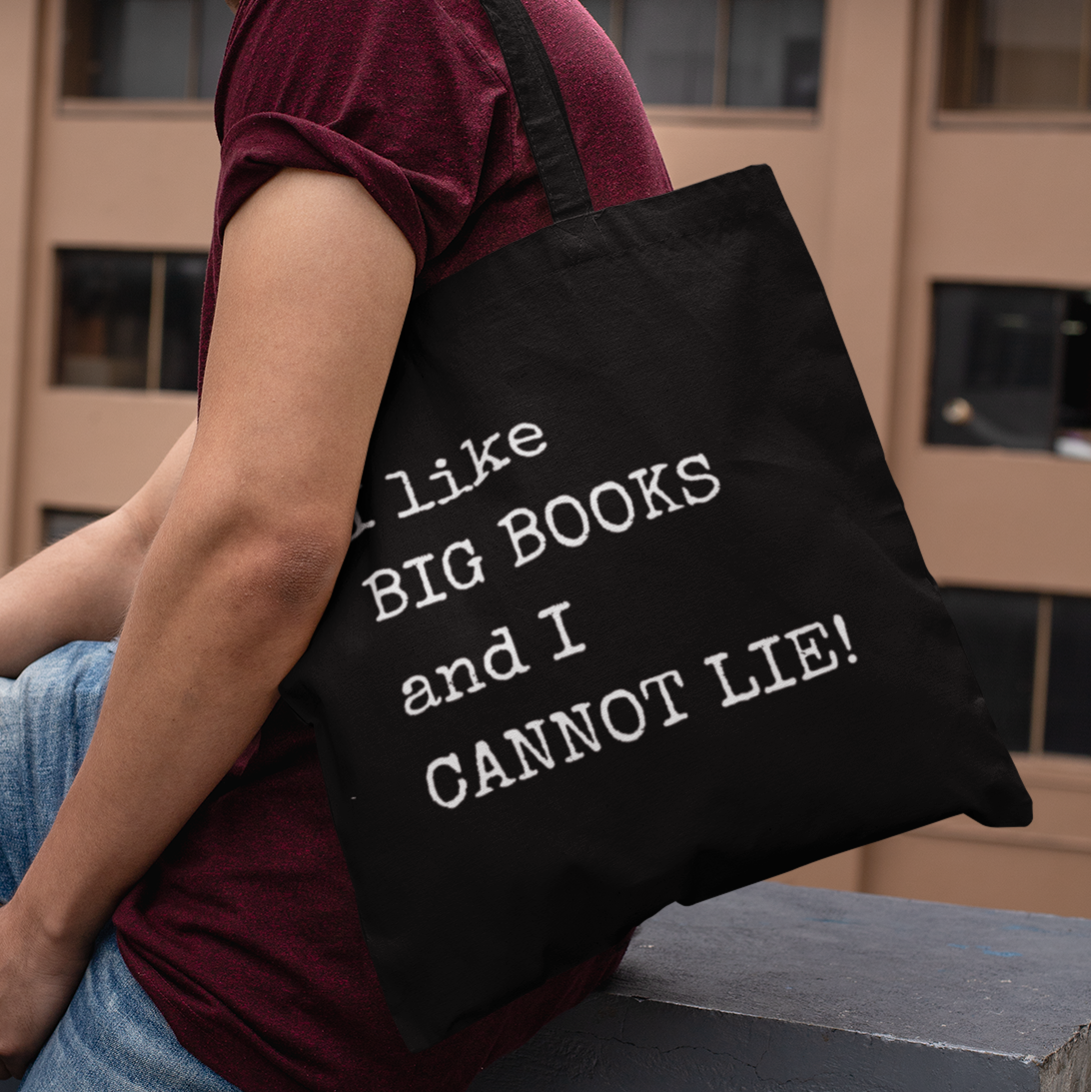 Man wearing maroon shirt and jeans carrying black tote bag with “I like BIG BOOKS and I CANNOT LIE!” quote – reading gift idea