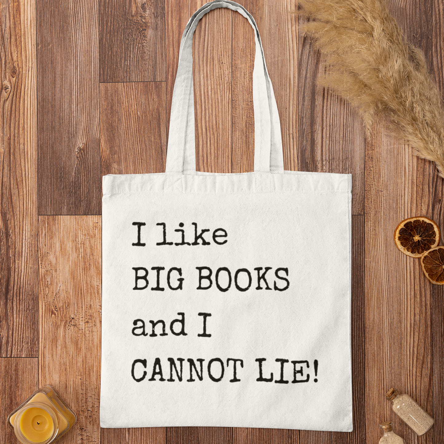 White minimalist tote bag with funny book quote “I like BIG BOOKS and I CANNOT LIE!” displayed on a wooden floor