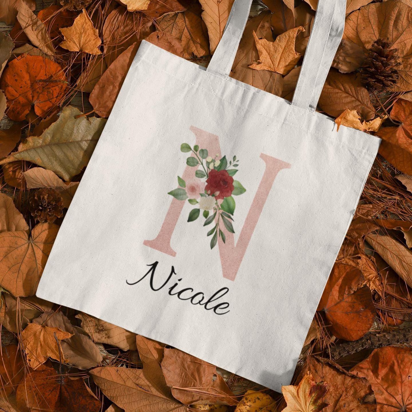 Blush Pink and Roses Floral Custom Tote Bag with initial N and name Nicole placed on autumn leaves background