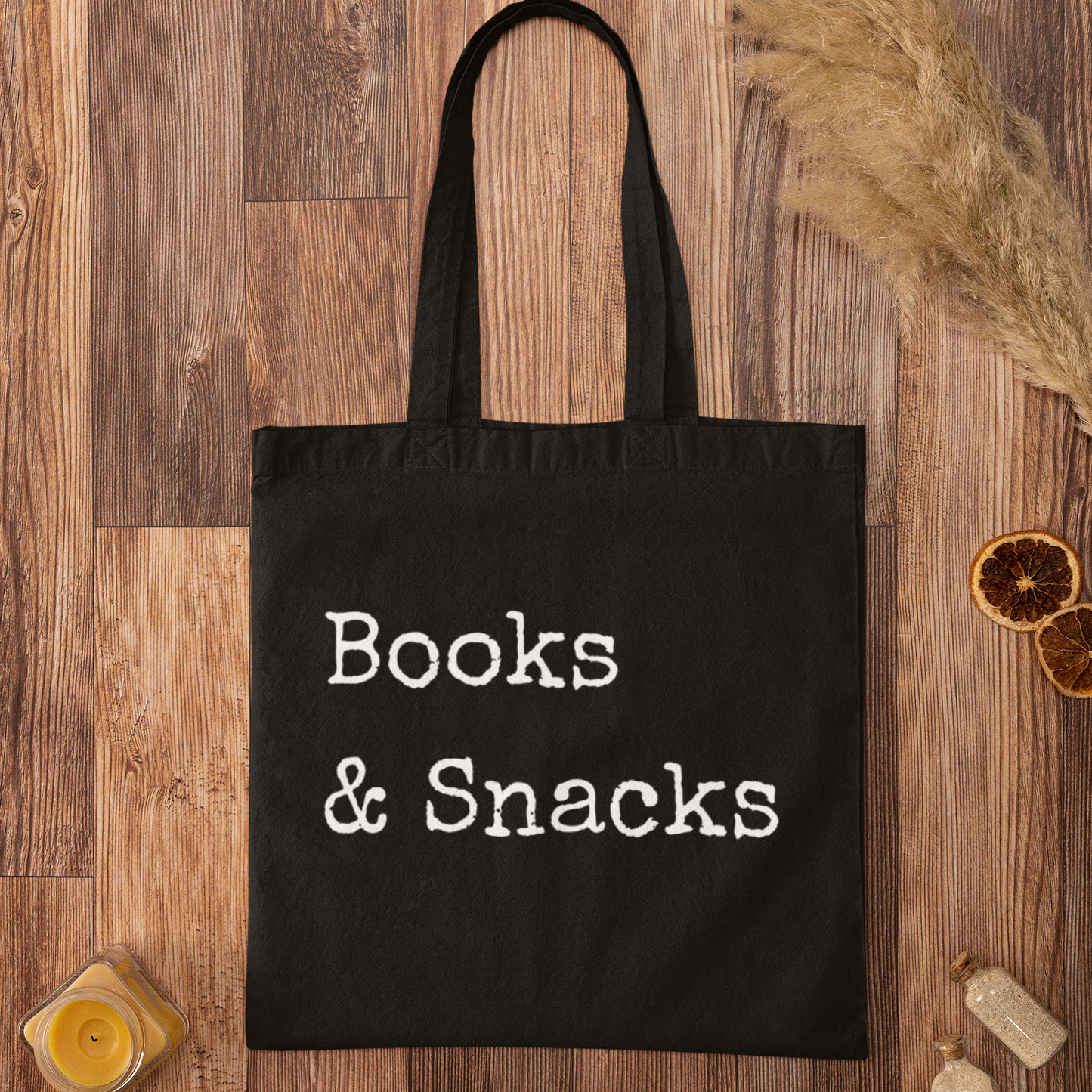 Books and Snacks black canvas tote bag flat lay on wooden background