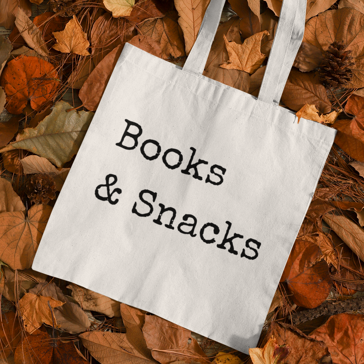 Books and Snacks quote canvas tote bag flat lay on autumn leaves background