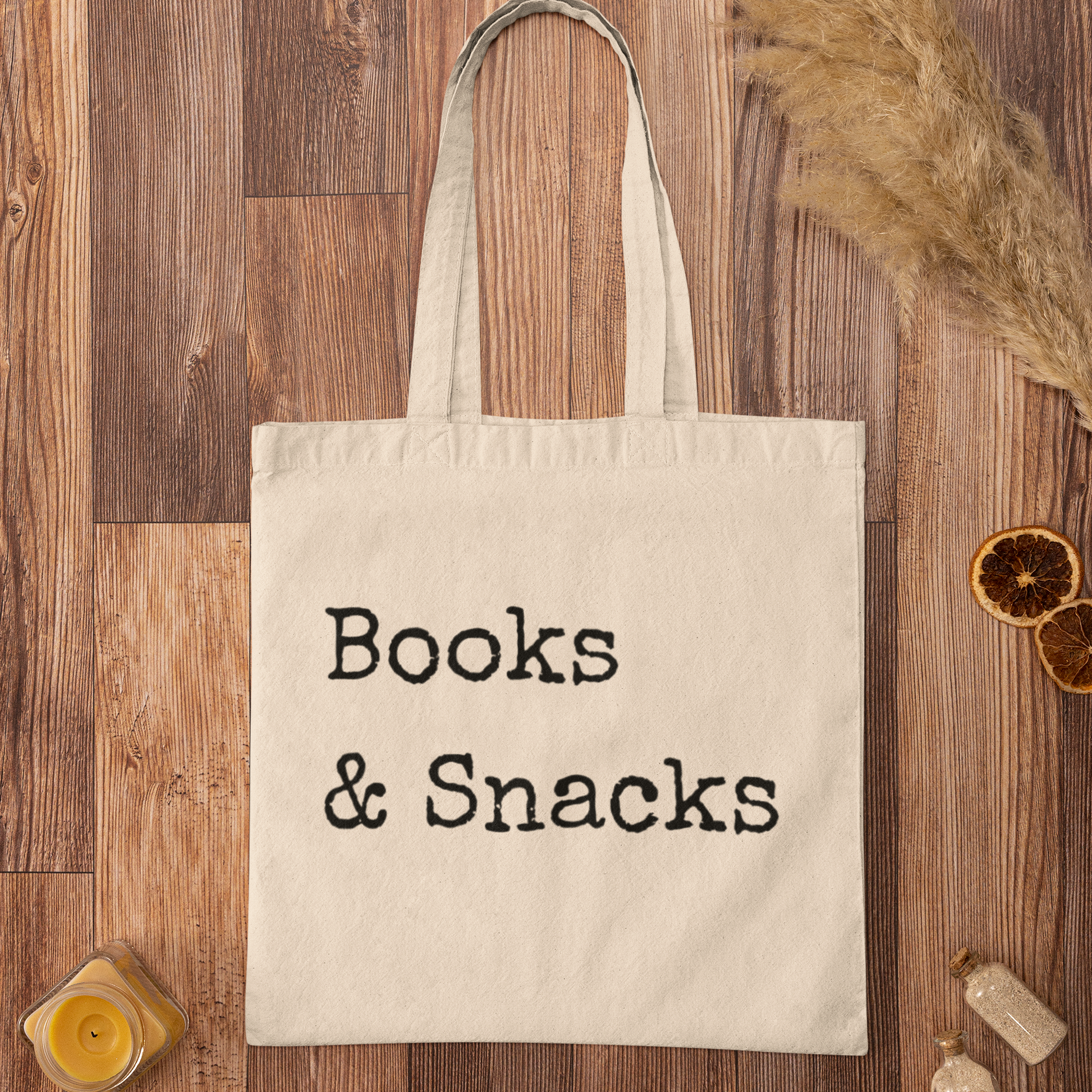 Books and Snacks quote printed on natural cotton canvas tote bag, flat lay