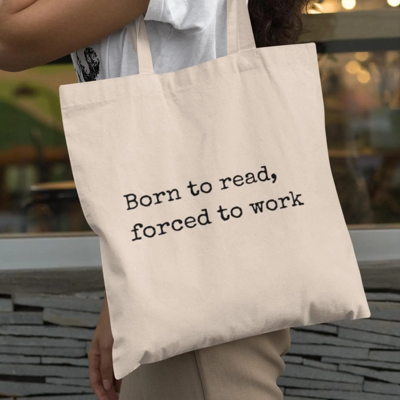 Natural canvas “Born to read, forced to work” tote bag carried by person — bookish eco bag