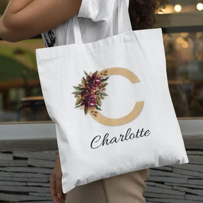 Personalized tote bag with letter C and burgundy flowers in gold style held by woman