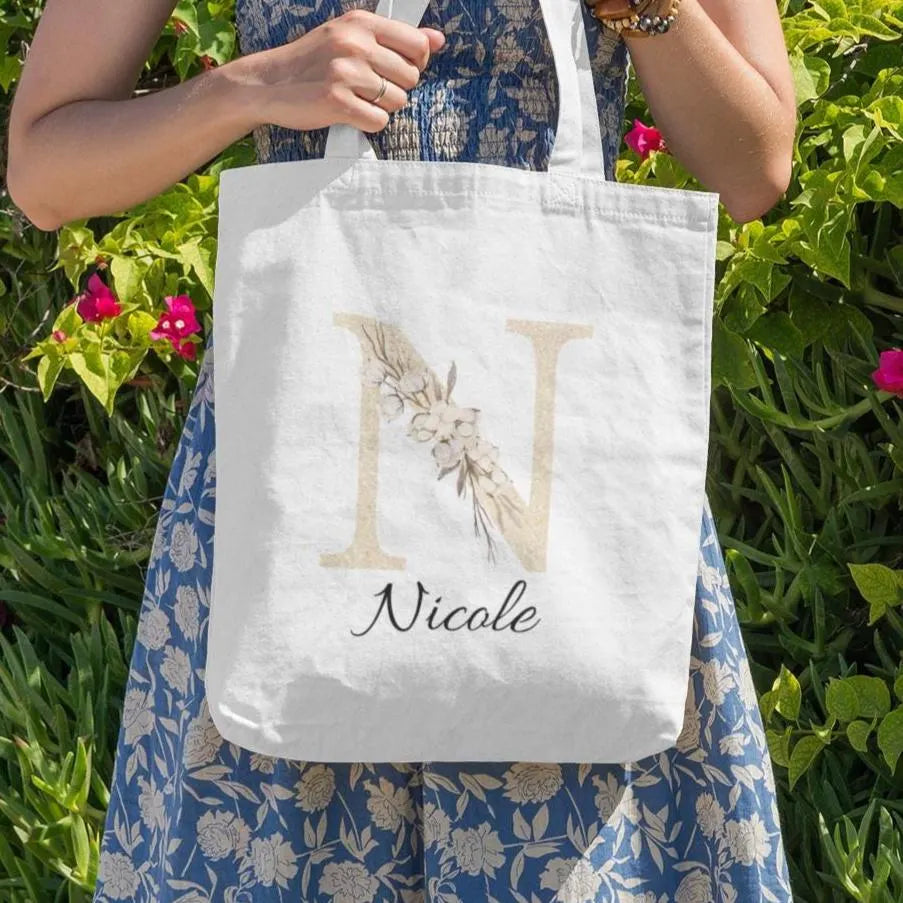 Champagne gold and ivory floral custom tote bag with initial, shown in a lifestyle setting being carried by a woman