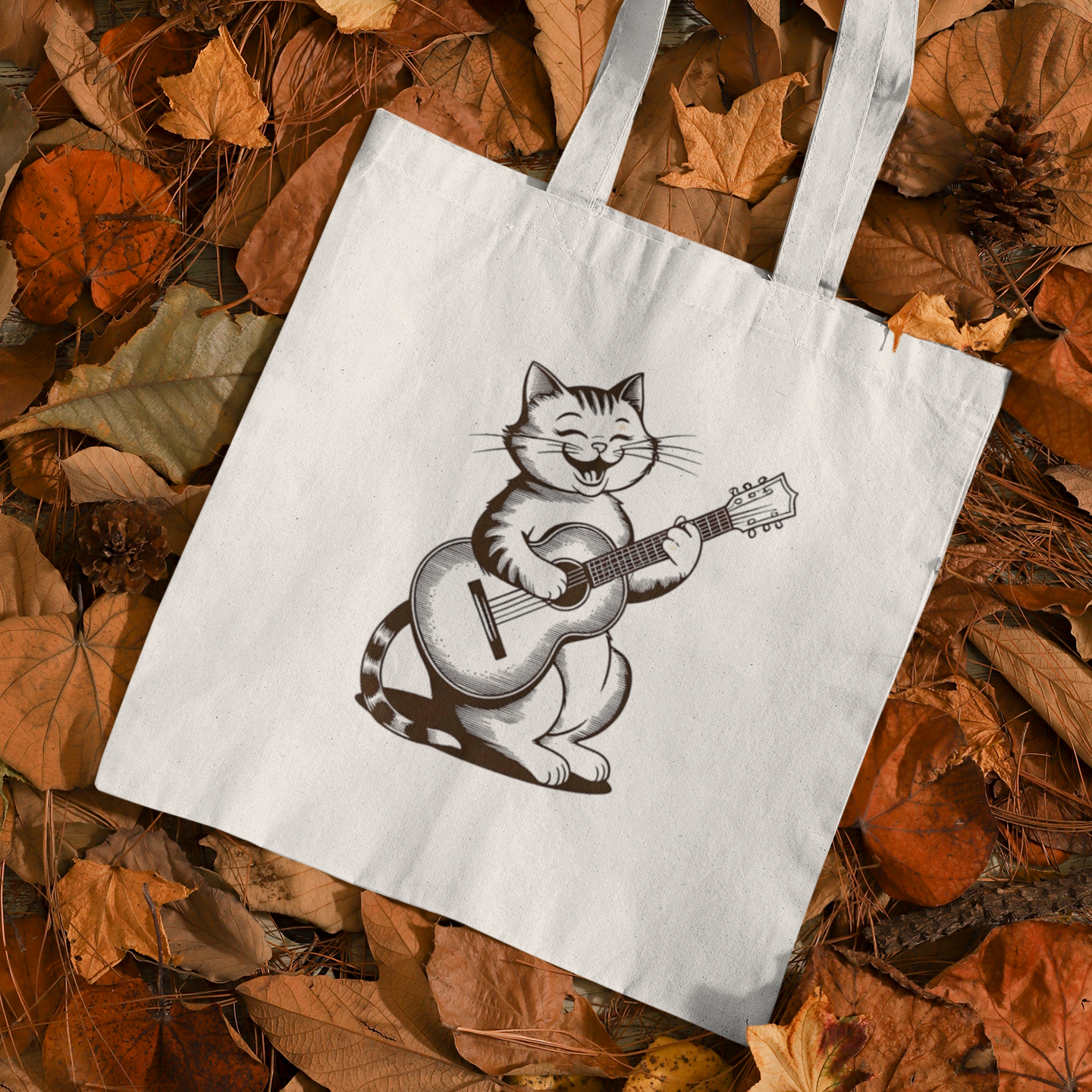 Cute Cat With Guitar Minimalist Tote Bag placed on autumn leaves background showcasing cozy seasonal style