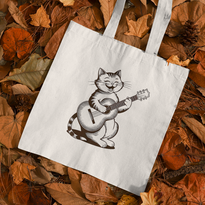 Cute Cat With Guitar Minimalist Tote Bag placed on autumn leaves background showcasing cozy seasonal style