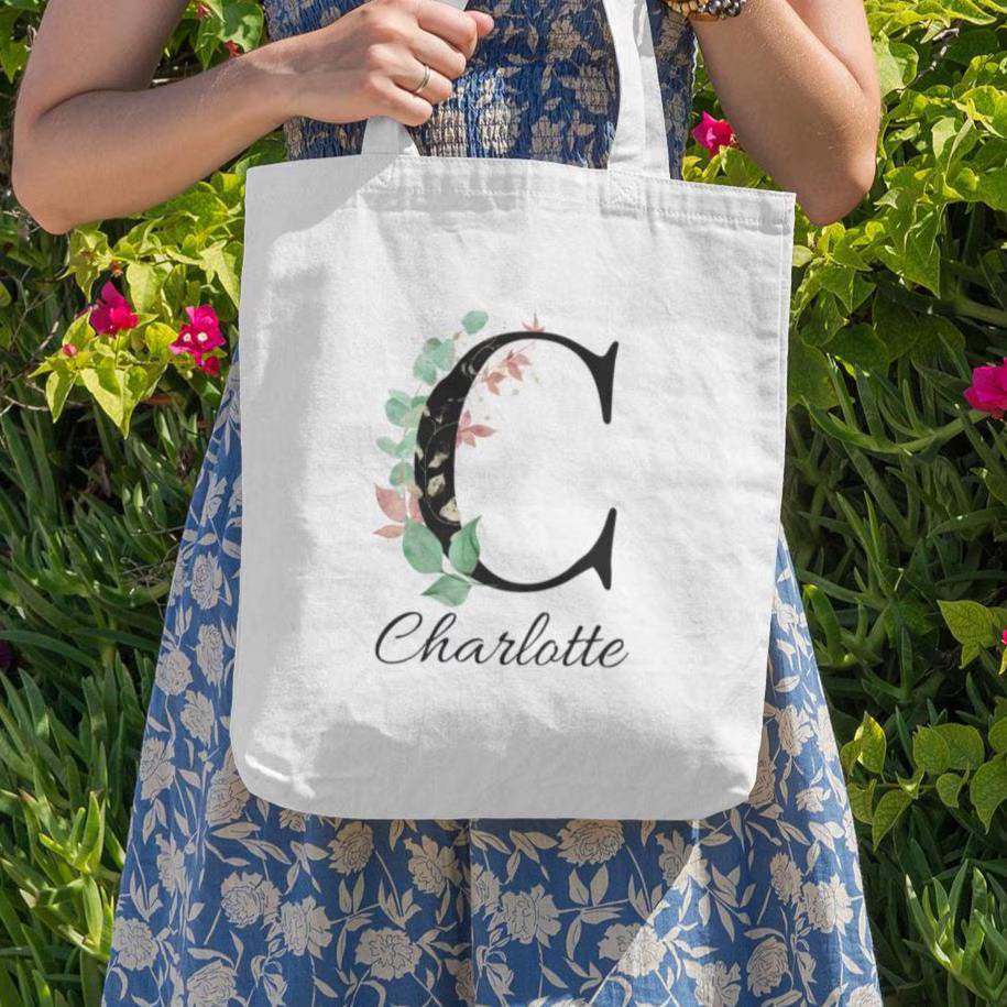 Outdoor lifestyle image of Charlotte holding Eucalyptus with Gold and Berry Leaf Initial Custom Tote Bag