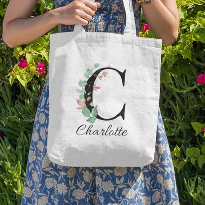 Outdoor lifestyle image of Charlotte holding Eucalyptus with Gold and Berry Leaf Initial Custom Tote Bag