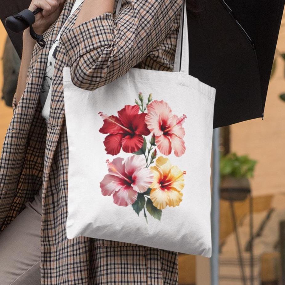 Person holding a tote bag with hibiscus floral design outdoors