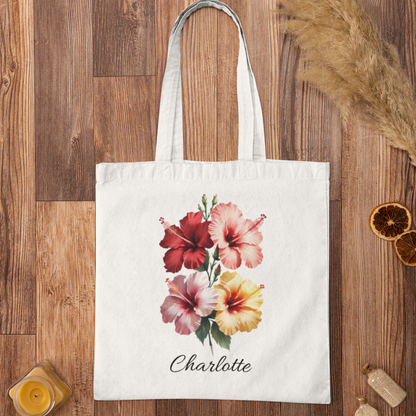 Tote bag with Hibiscus floral design and 'Charlotte' text on a wooden surface