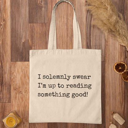 Natural cotton I Solemnly Swear Reading Quote tote bag on rustic wooden background, minimalist design for readers.