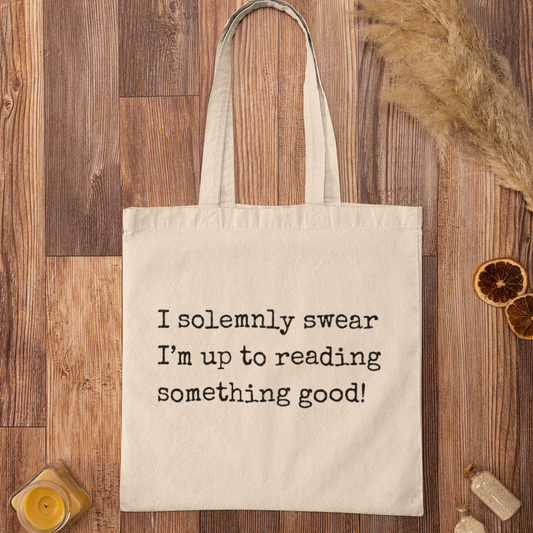 Natural cotton I Solemnly Swear Reading Quote tote bag on rustic wooden background, minimalist design for readers.