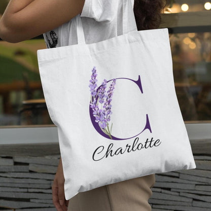 Woman carrying a Lavender Floral Custom Tote Bag With Purple Initial “C” outdoors