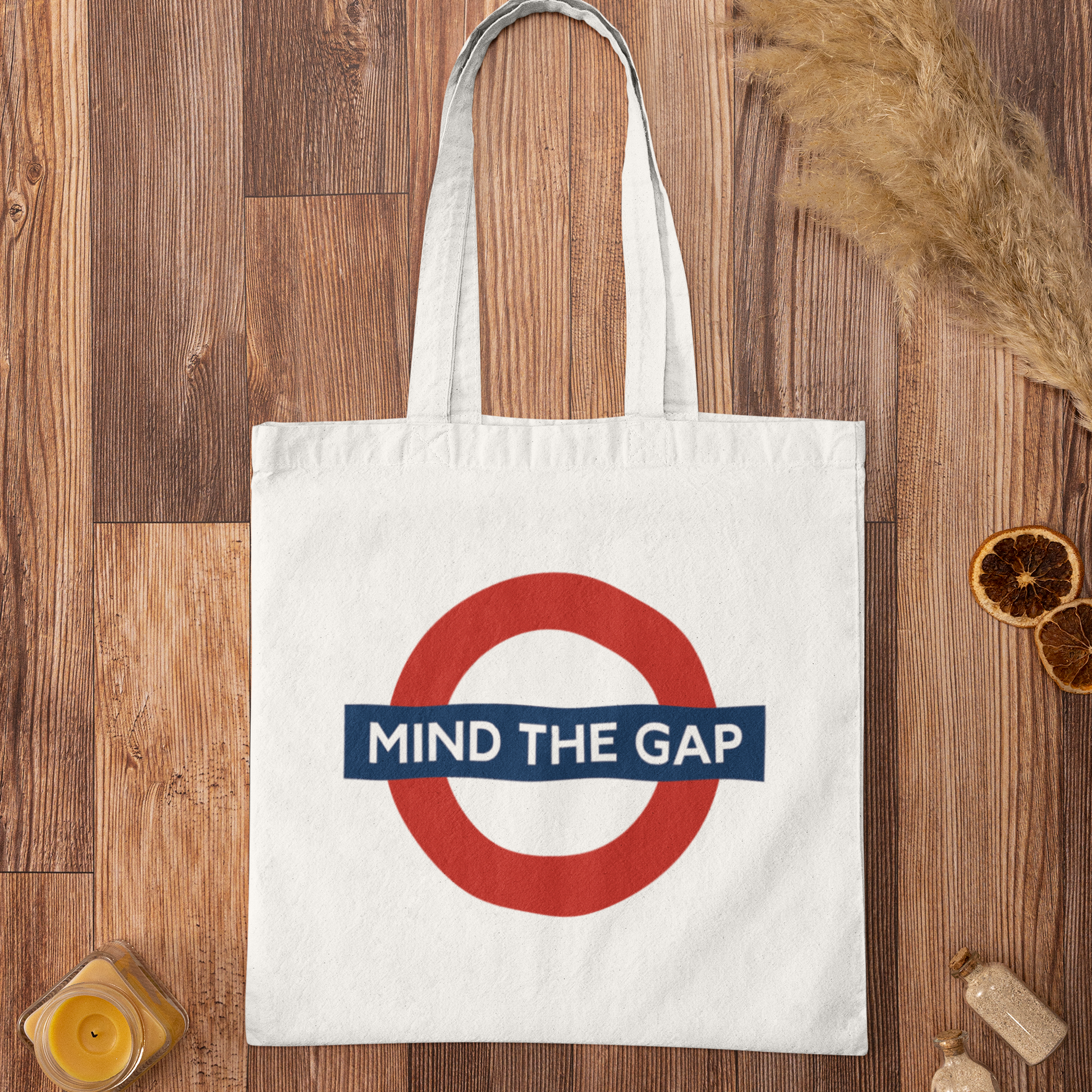 Mind The Gap graphic tote bag flatlay on rustic wooden background – eco-friendly London city streetwear bag