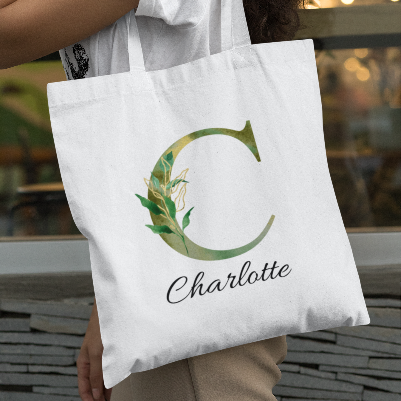 Woman carrying olive green foliage initial tote bag with letter C and name Charlotte, personalized botanical gift
