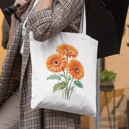 Woman carrying white floral tote bag with orange gerbera design and name Nicole printed on front.