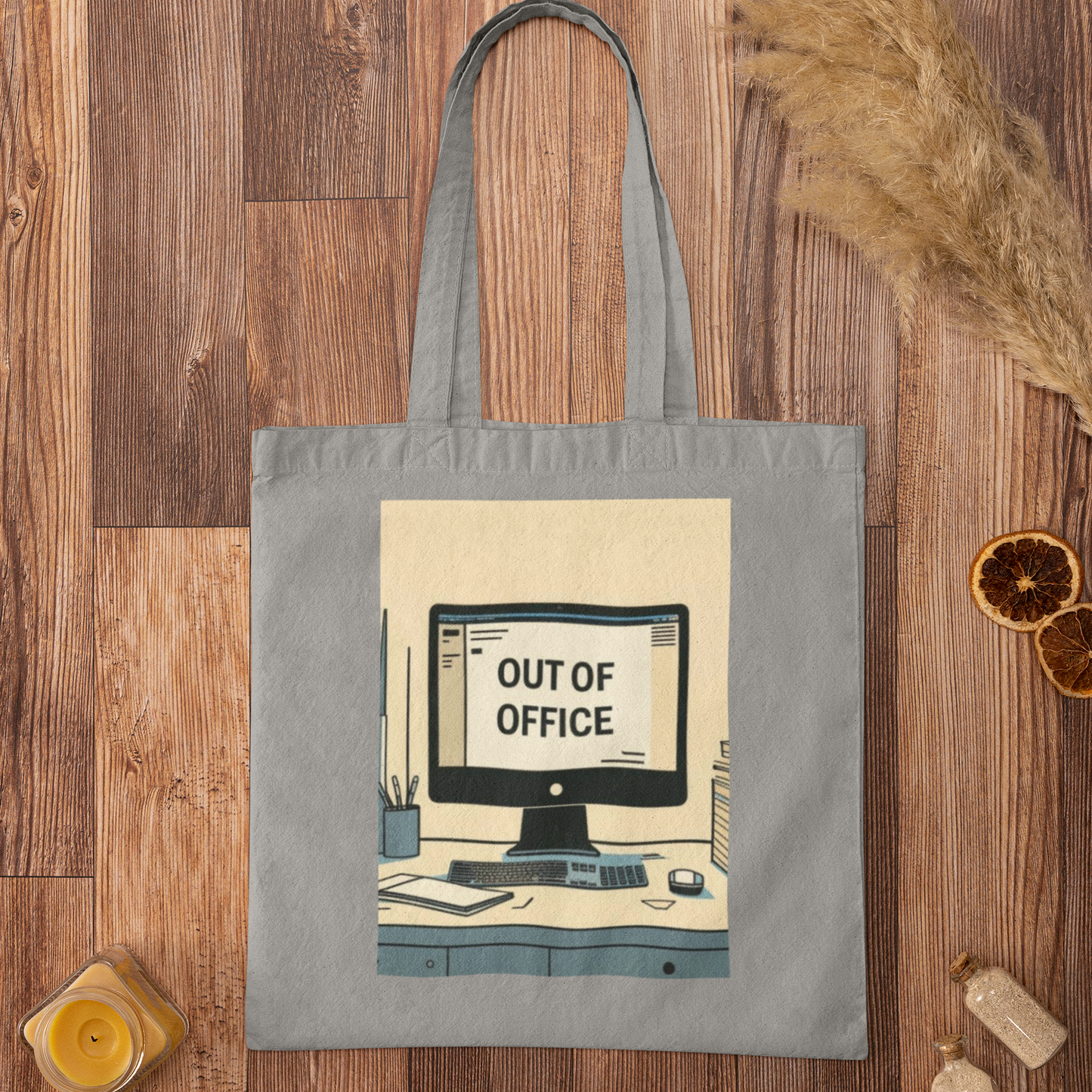 Grey Out of Office Design Graphic Tote Bag flatlay on wooden surface with dried flowers and accessories