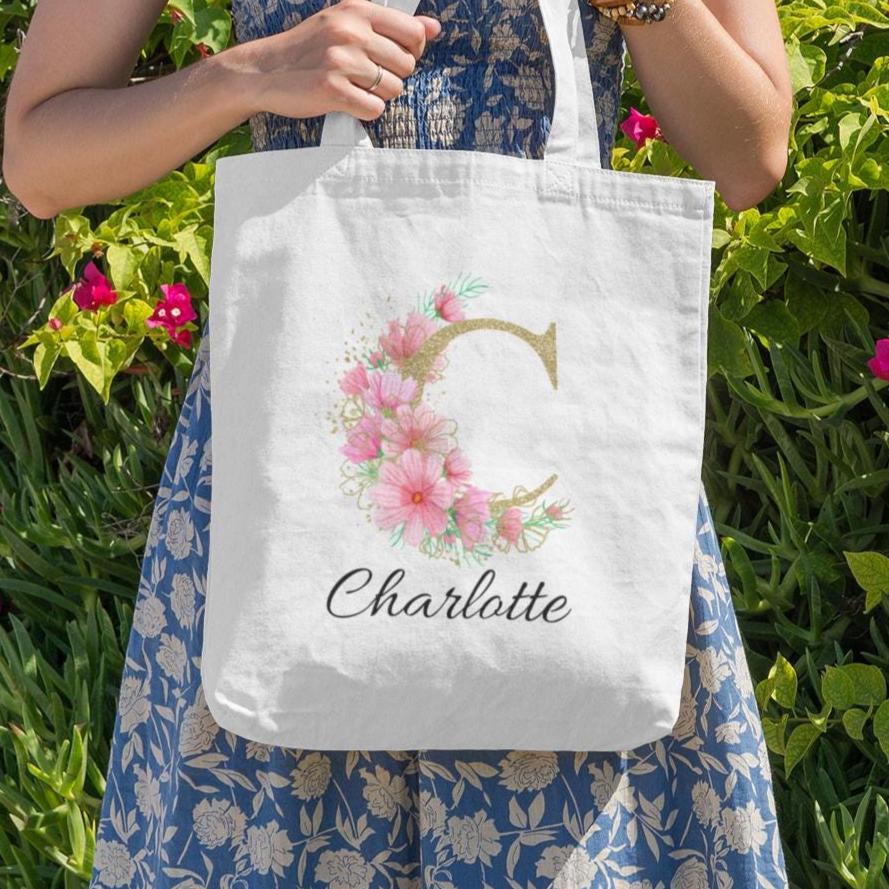 Custom initial tote bag with letter C and name Charlotte, pink and gold pastel floral design, garden-inspired aesthetic