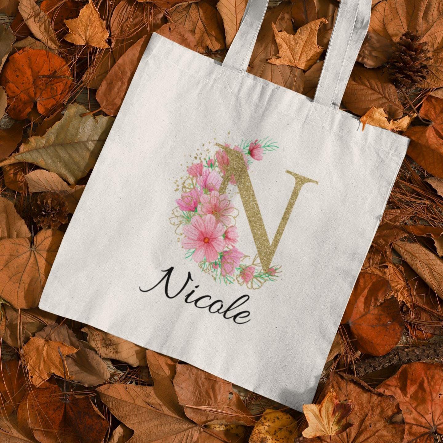 Personalised tote bag with letter N and name Nicole, featuring pink pastel flowers and gold initial on autumn leaf background