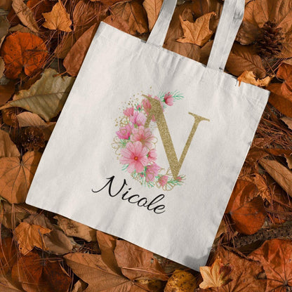 Personalised tote bag with letter N and name Nicole, featuring pink pastel flowers and gold initial on autumn leaf background