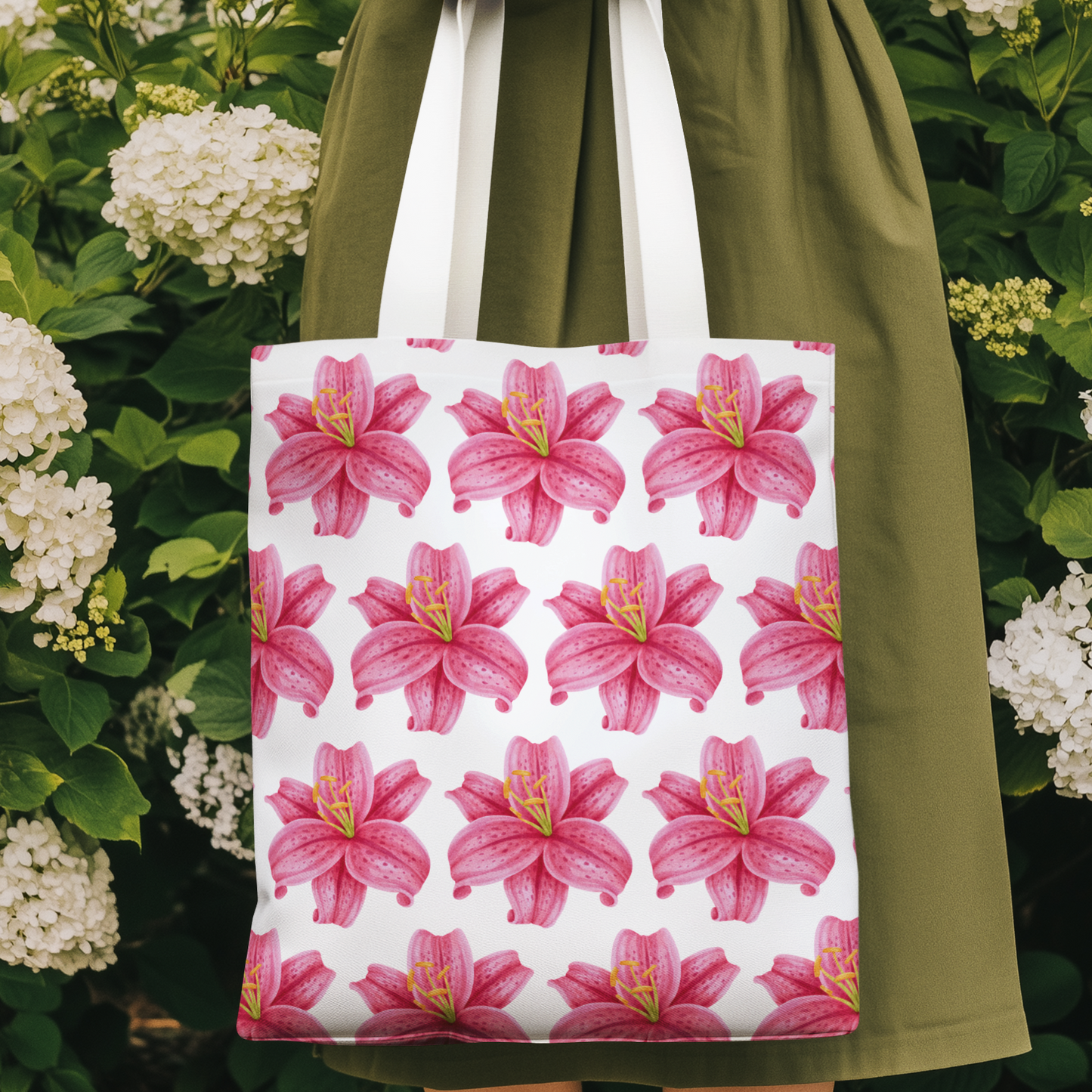 Pink lily flower design tote bag with floral pattern held by woman in a garden