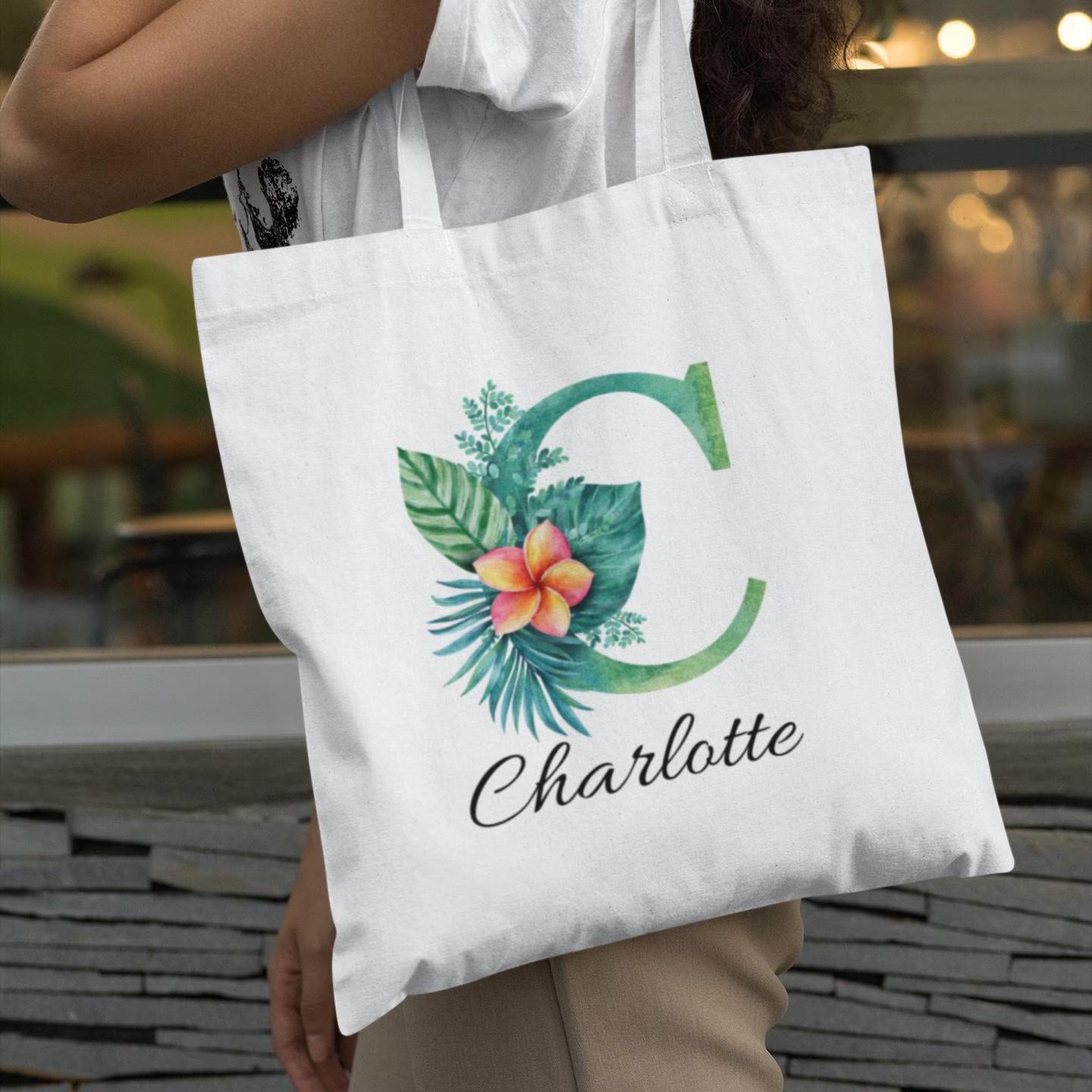 Charlotte holding Plumeria Tropical Floral Custom Tote Bag with Emerald Green Initial C, personalized tropical gift idea
