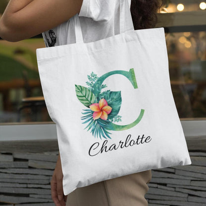 Charlotte holding Plumeria Tropical Floral Custom Tote Bag with Emerald Green Initial C, personalized tropical gift idea