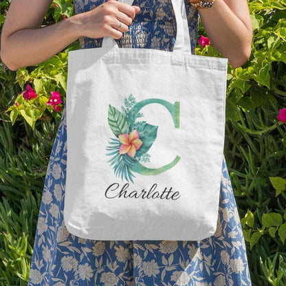 Charlotte carrying Plumeria Tropical Floral Custom Tote Bag with Emerald Green Initial C, tropical floral personalized tote outdoors
