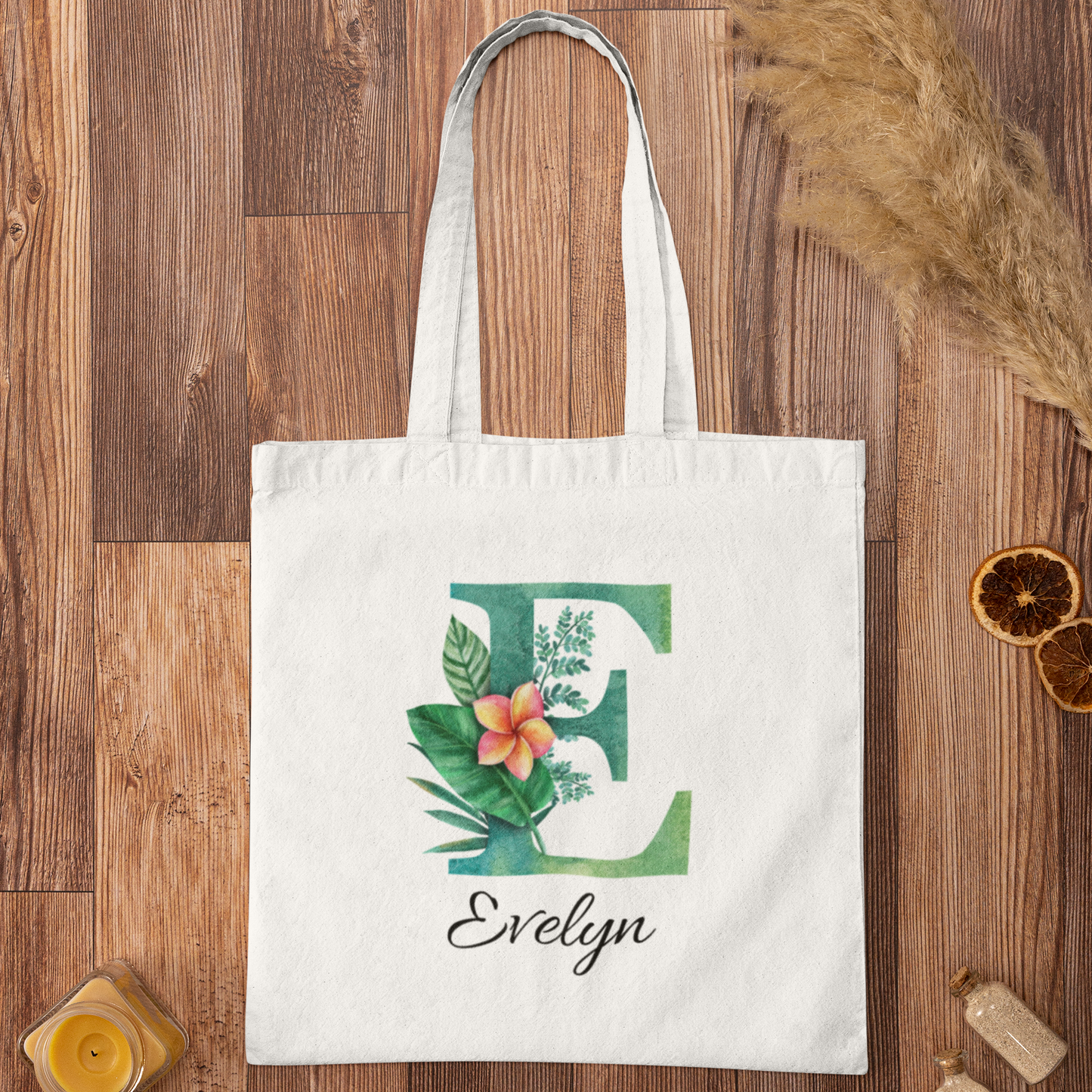 Plumeria Tropical Floral Custom Tote Bag with Emerald Green Initial E, personalized name Evelyn, flatlay on wooden background