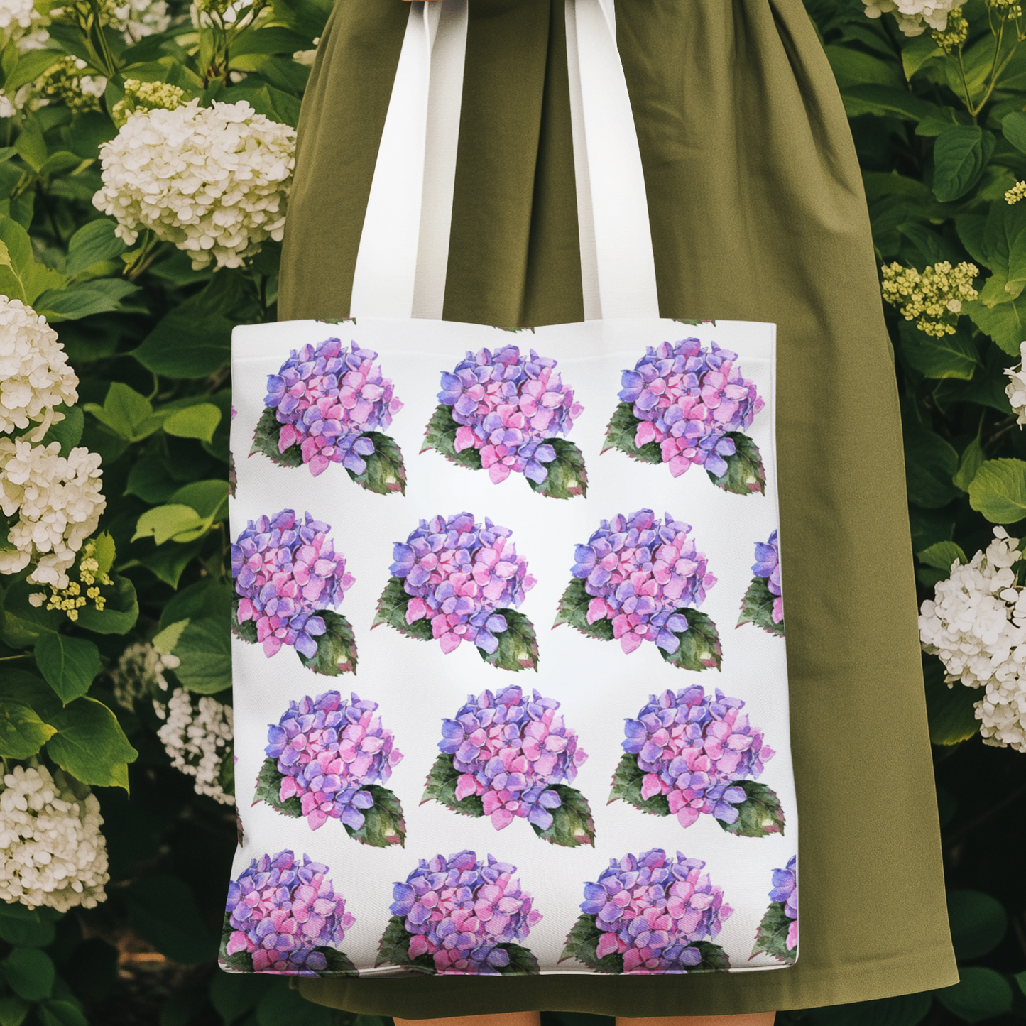 Woman holding Hydrangea Patterned Floral Design Tote Bag with pink hydrangea print among blooming flowers