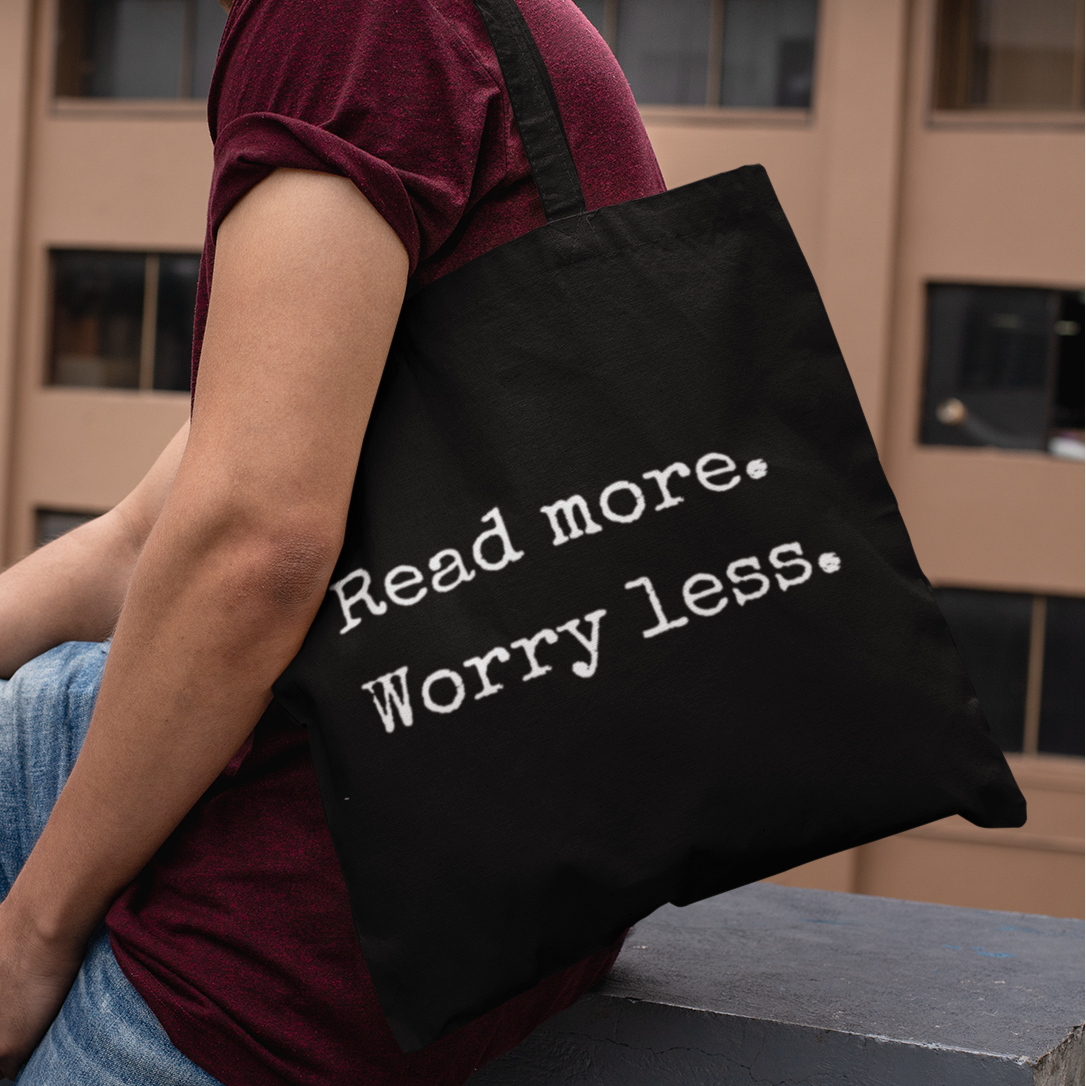 Man carrying black tote bag with ‘Read more. Worry less.’ quote – minimalist literary tote bag for readers