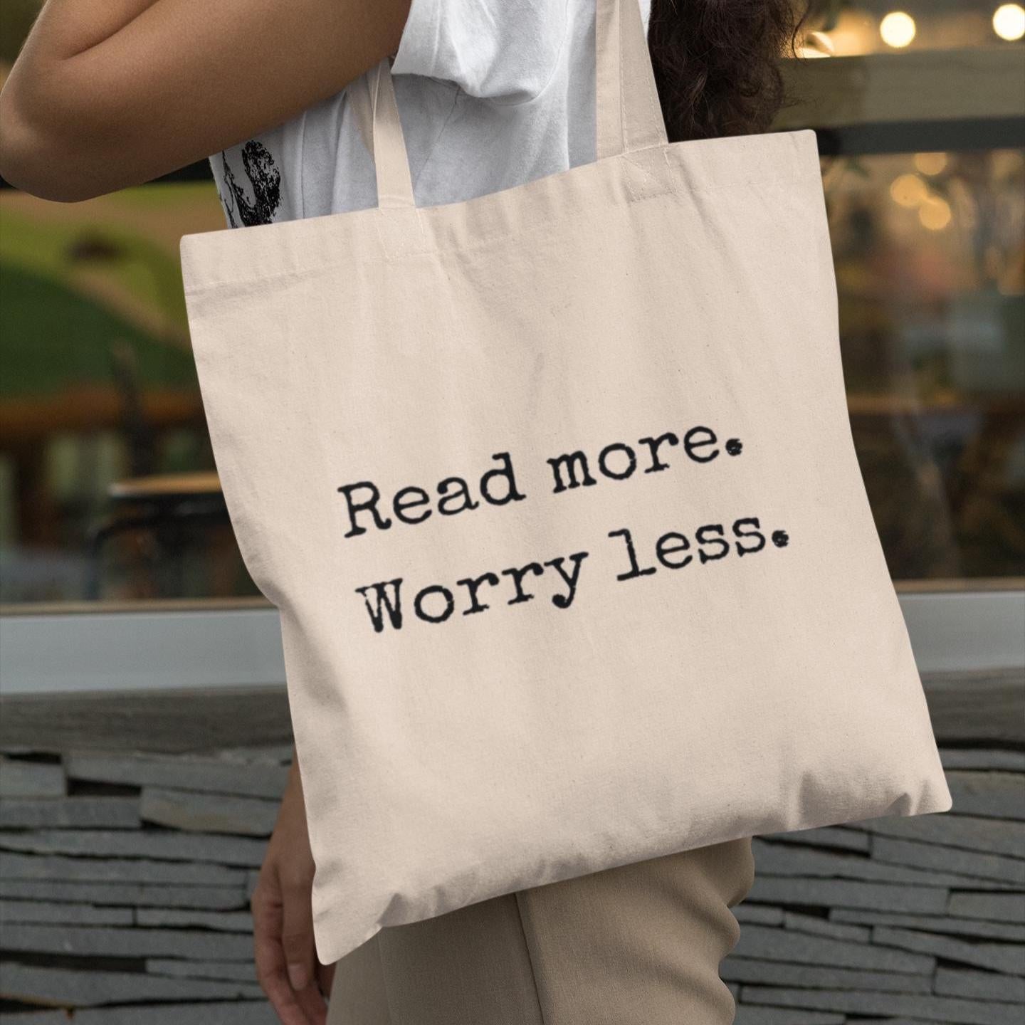 Woman carrying natural canvas tote bag printed with ‘Read more. Worry less.’ – stylish book lover accessory