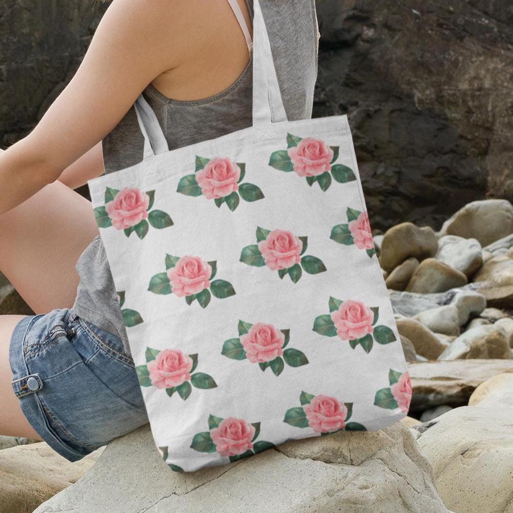 Rose Pattern Flower Design Tote Bag placed on rocks near the beach, displaying the pink rose pattern