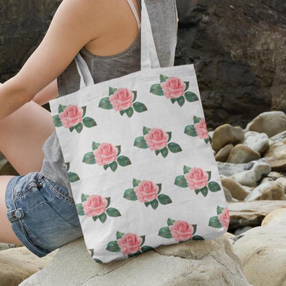 Rose Pattern Flower Design Tote Bag placed on rocks near the beach, displaying the pink rose pattern