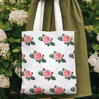 Woman holding a rose pattern tote bag with pink roses and green leaves, standing in a garden surrounded by blooming hydrangeas