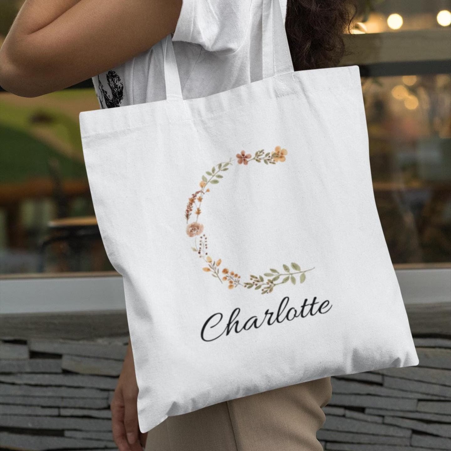 Woman carrying rustic floral initial tote bag with letter C and name Charlotte, personalized gift idea