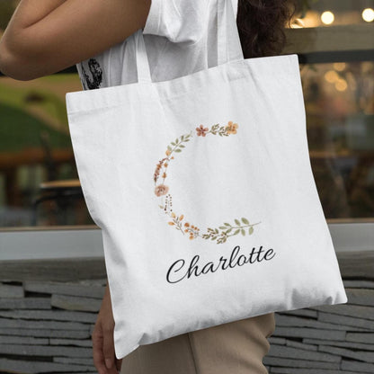 Woman carrying rustic floral initial tote bag with letter C and name Charlotte, personalized gift idea