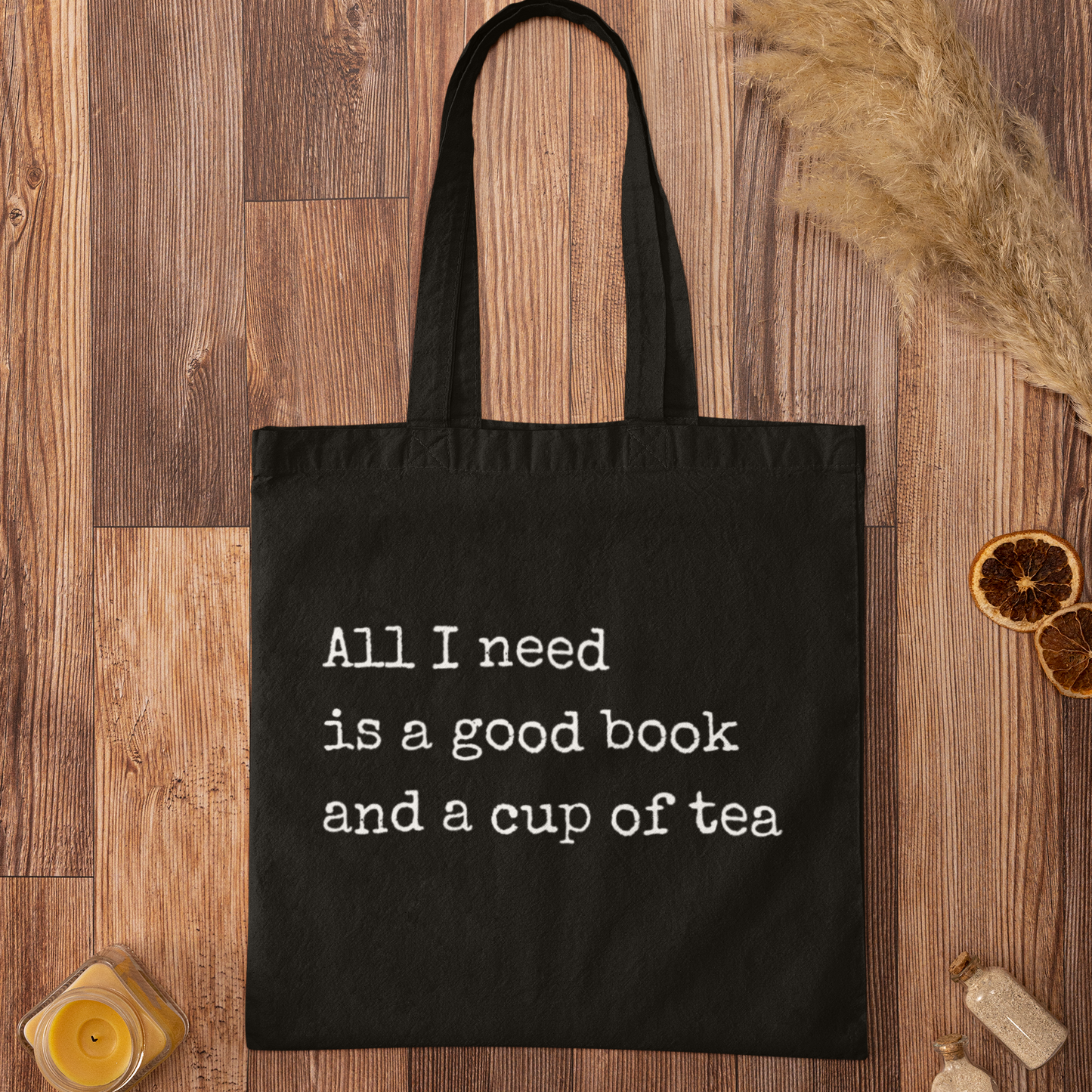 Black cotton tote bag with typewriter-style quote 'All I need is a good book and a cup of tea' – minimalist reading quote tote for book lovers