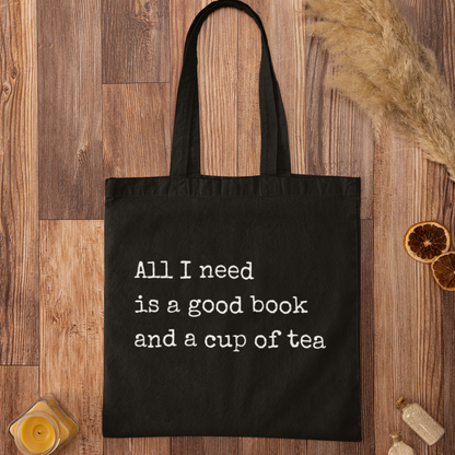Black cotton tote bag with typewriter-style quote 'All I need is a good book and a cup of tea' – minimalist reading quote tote for book lovers
