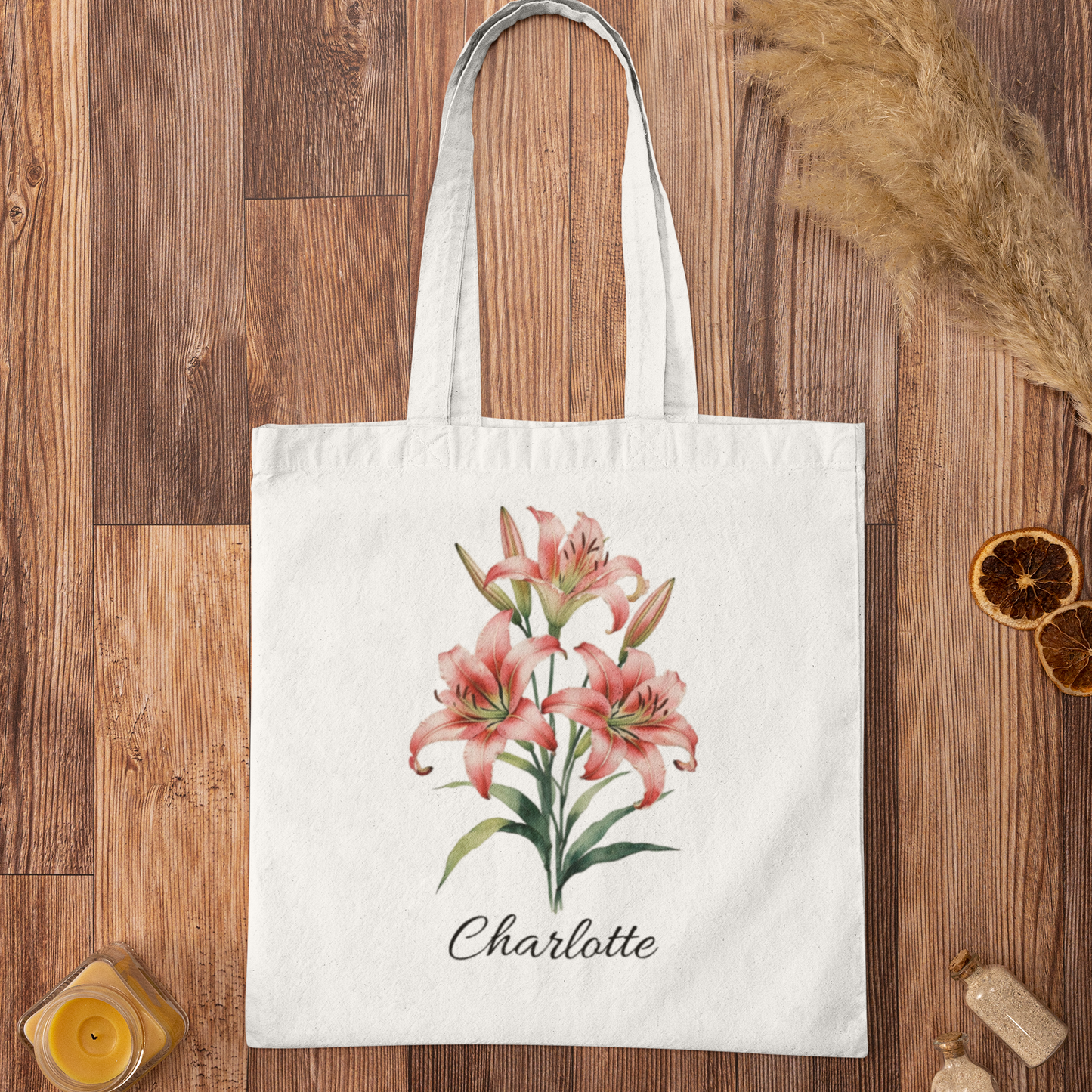 White tote bag with tiger lily floral design and 'Charlotte' text on a wooden surface