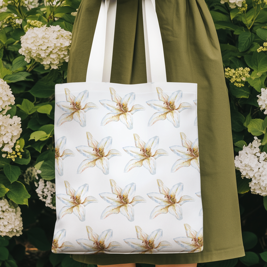 White Lily Flower Design Patterned Tote Bag displayed outdoors surrounded by blooming hydrangeas.