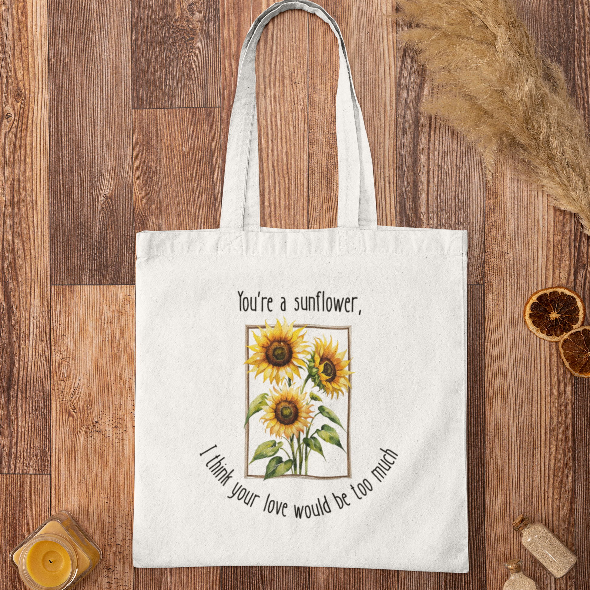 White tote bag with sunflower design and text on a wooden surface